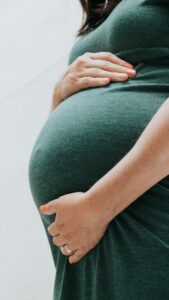 Woman experiencing early pregnancy symptoms including fatigue, nausea, food cravings, and mood swings.